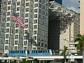 Royalty Free Stock Video HD Footage American Flag Waving with High Rise Condos and Office Buildings as Double People Mover Car Passes by in Downtown Miami,  Florida