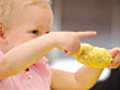 Little girl points with her corn in hand