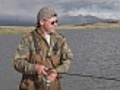 Fisherman with spinning pull fish from mountain lake Dayan Nuur