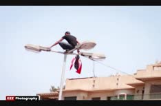 سبايدرمان المصري يتسلق أحد أعمدة الإنارة ليرفع علم مصر