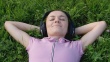 Attractive woman lying on grass and listening to music