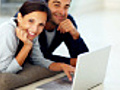 Joyful young couple using laptop while lying on floor