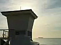 Royalty Free Stock Video HD Footage Static Shot Life Guard Stand and Ft. Lauderdale Beach at Sunrise with Ships on Horizon