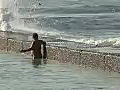 Royalty Free Stock Video HD Footage Woman and Waves Crashing Over Sea Wall at Waikiki Beach in Honolulu,  Hawaii