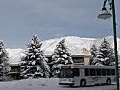 Royalty Free Stock Video HD Footage Pan Left as Bus Passes on a Snow Covered Street,  Then Zoom Into Child Being Pulled on a Sled on a Winter’s Day in Beaver Creek, Colorado