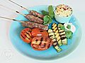 Lamb kebab skewers with cooked tomatoes and courgettes