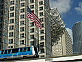 Royalty Free Stock Video HD Footage American Flag Waving with High Rise Condos and Office Buildings as People Mover Car Passes by in Downtown Miami,  Florida