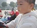 Shallow DOF,  asian kid sitting on carousel smiling and grinning.